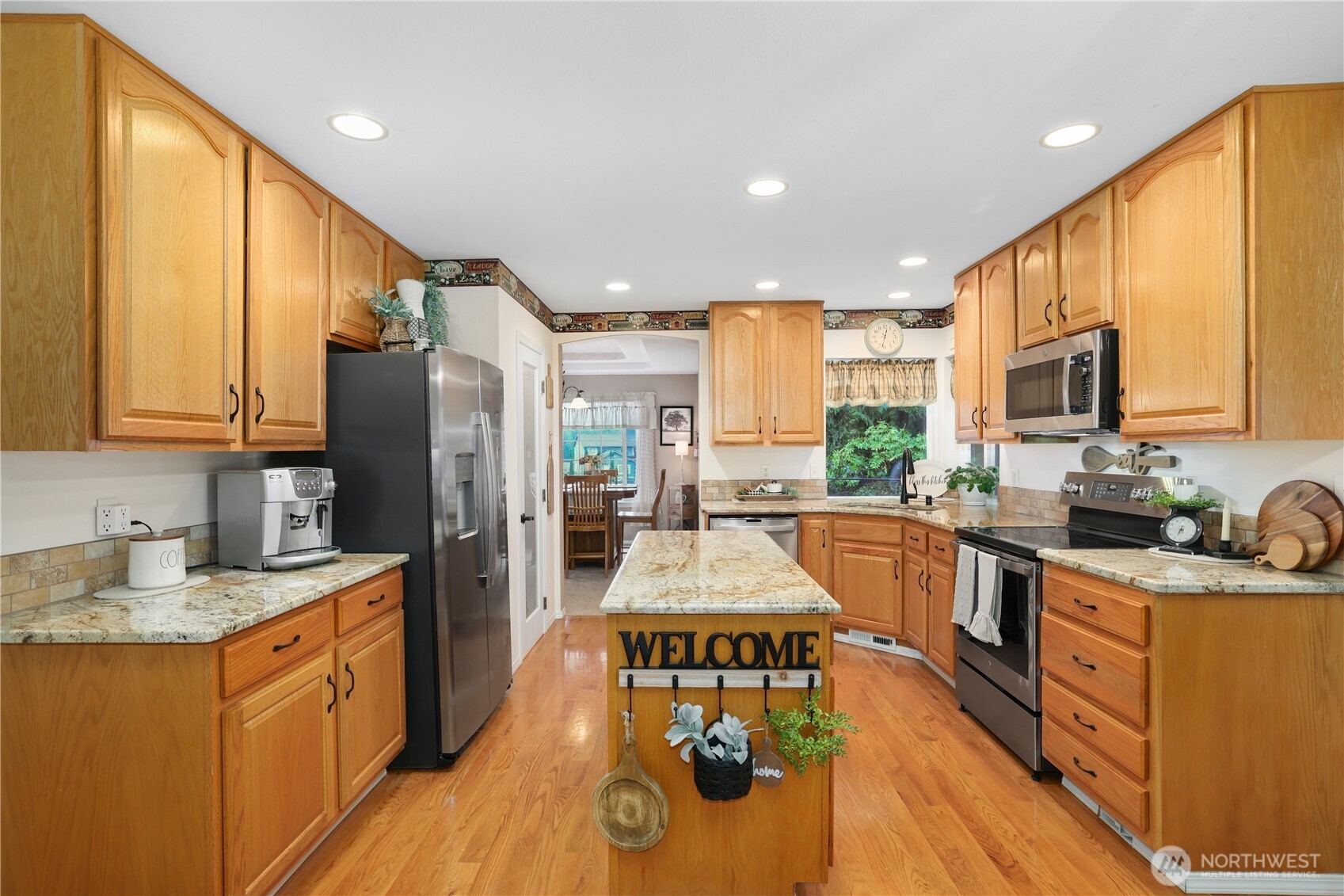 12722 247th Street East Graham, WA 98338 - Photo 12 of 40 a kitchen with stainless steel appliances granite countertop a sink a stove top oven a refrigerator cabinets and living room view