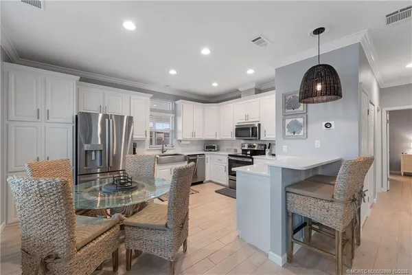 a kitchen with granite countertop stainless steel appliances a refrigerator a stove a sink a dining table and chairs