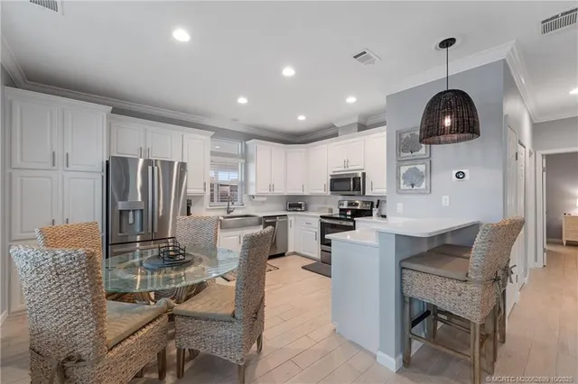 a kitchen with granite countertop stainless steel appliances a refrigerator a stove a sink a dining table and chairs