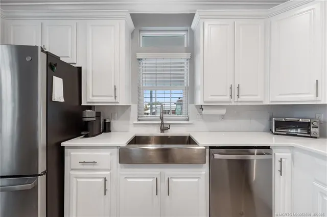 a kitchen with granite countertop white cabinets and refrigerator