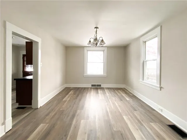 an empty room with wooden floor cabinet and windows