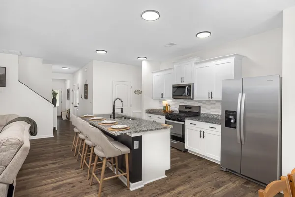 a kitchen with stainless steel appliances granite countertop a table chairs sink refrigerator and microwave