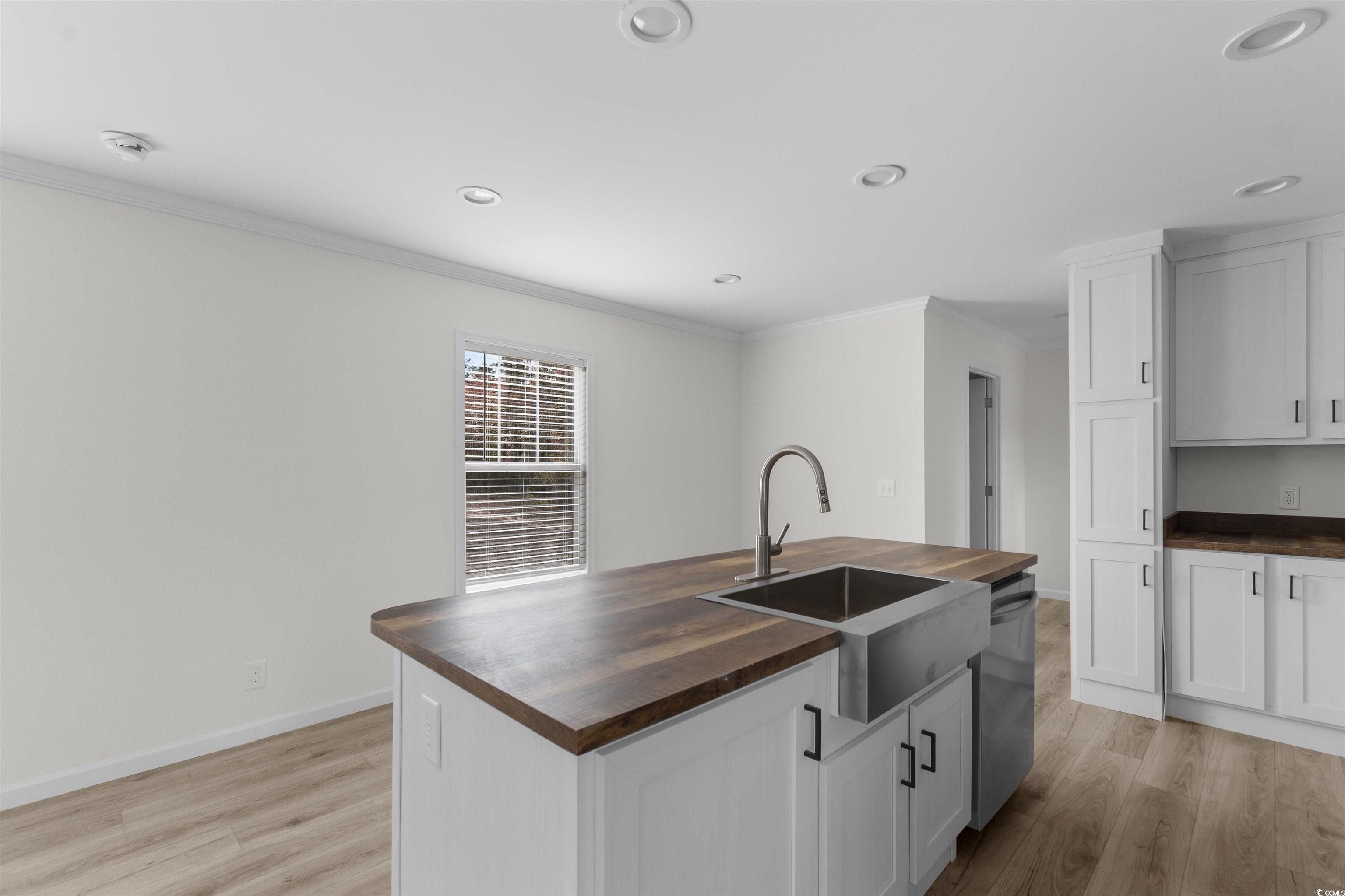 141 Feather Drive Georgetown, SC 29440 - Photo 13 of 34 Kitchen with wooden counters, a center island with sink, crown molding, light wood finished floors, and white cabinetry