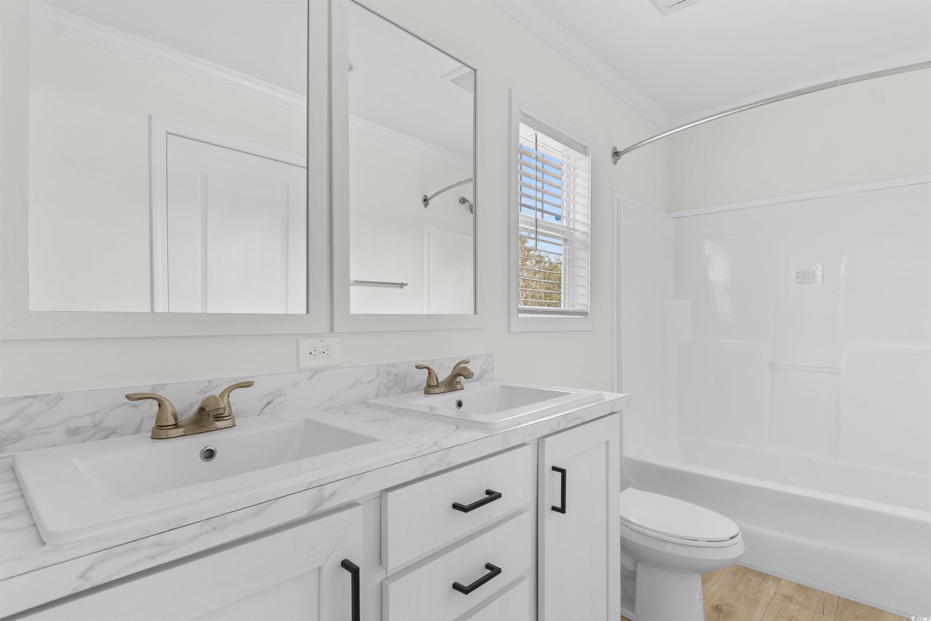 141 Feather Drive Georgetown, SC 29440 - Photo 19 of 34 Bathroom with shower combination, double vanity, ornamental molding, and light wood-type flooring