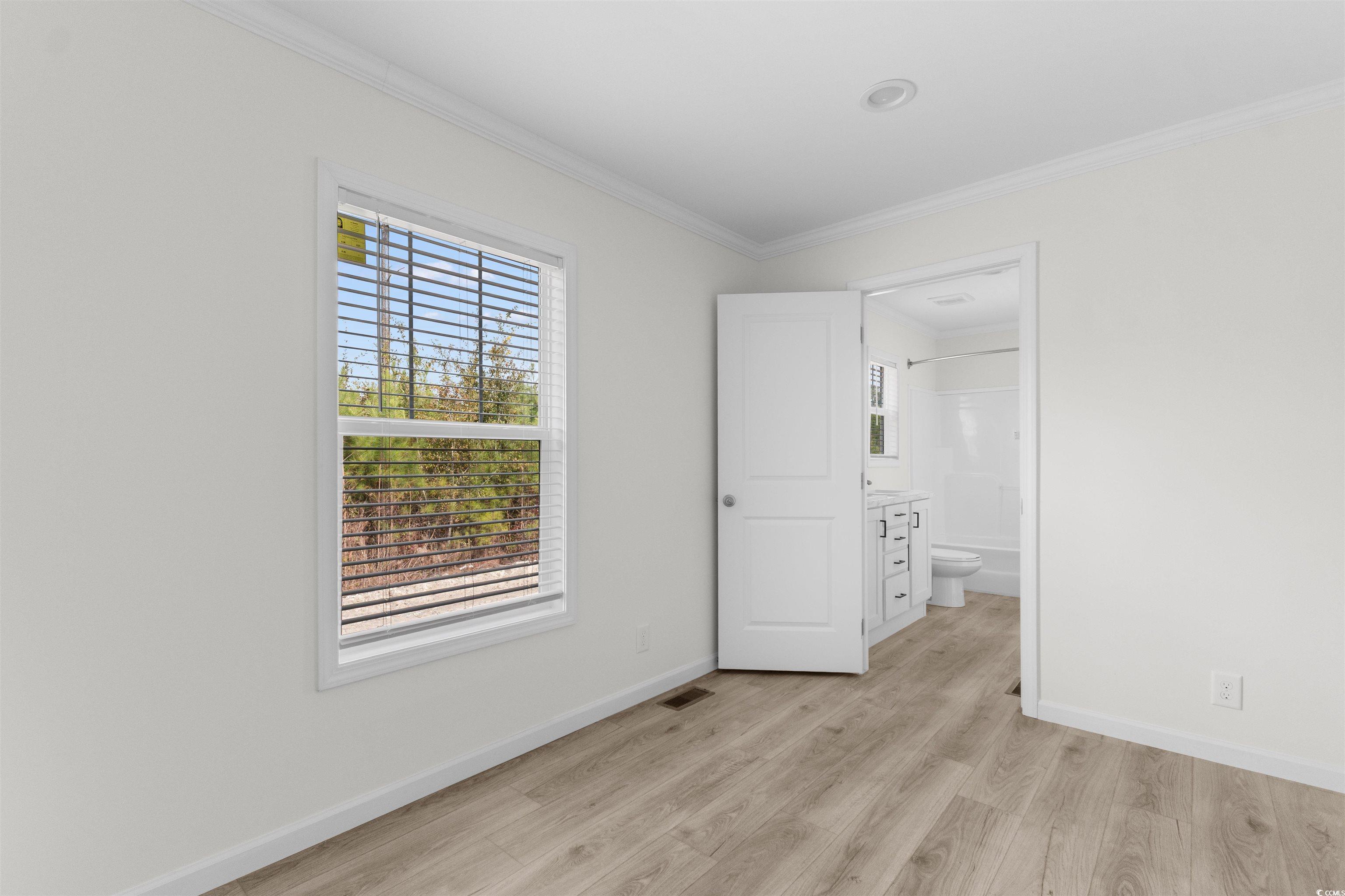 141 Feather Drive Georgetown, SC 29440 - Photo 20 of 34 Unfurnished bedroom featuring crown molding, light wood finished floors, and ensuite bathroom
