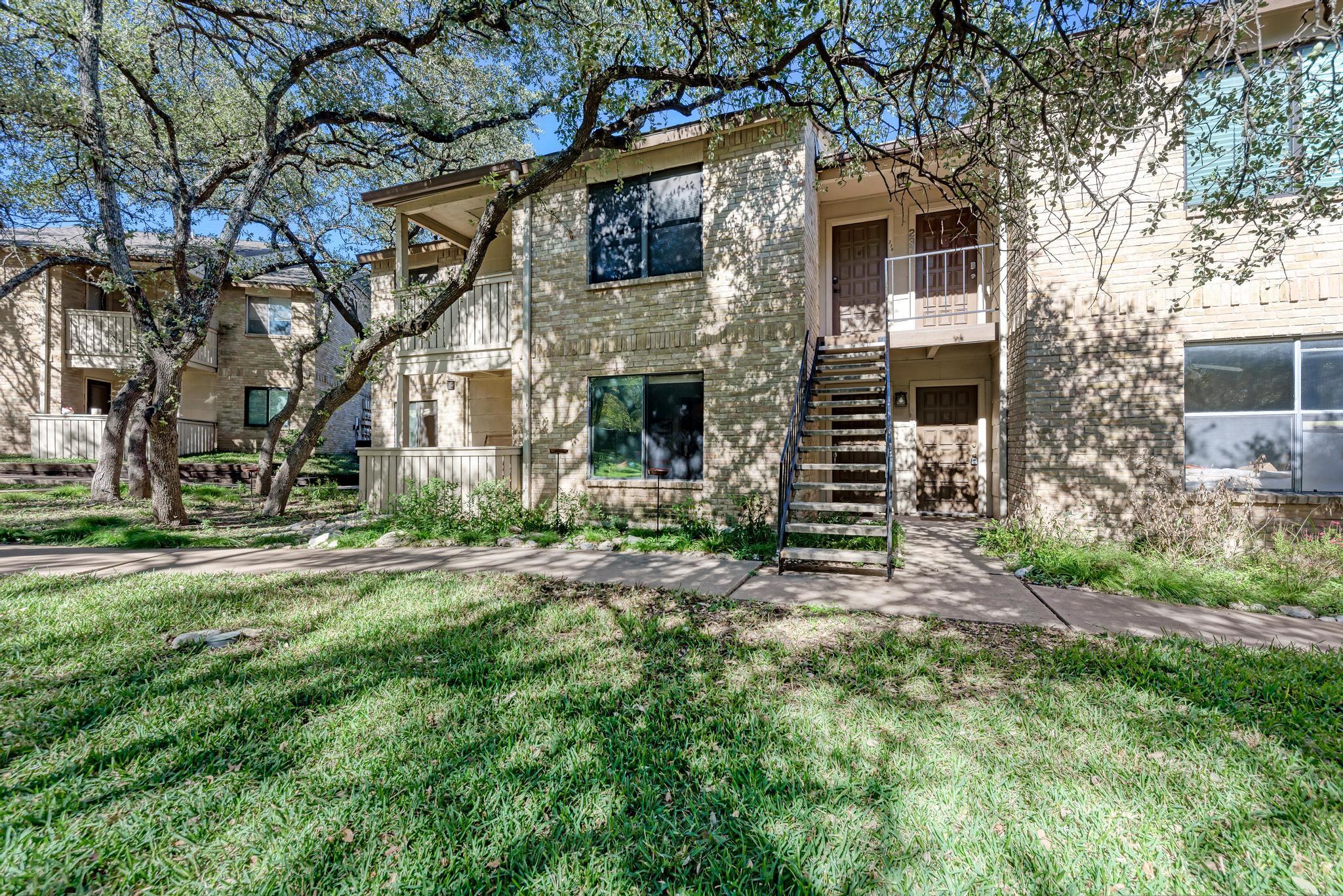 8210 Bent Tree Road, Unit 136 Austin, TX 78759 - Photo 18 of 20 View of front facade with brick siding, a front lawn, stairway, and a balcony