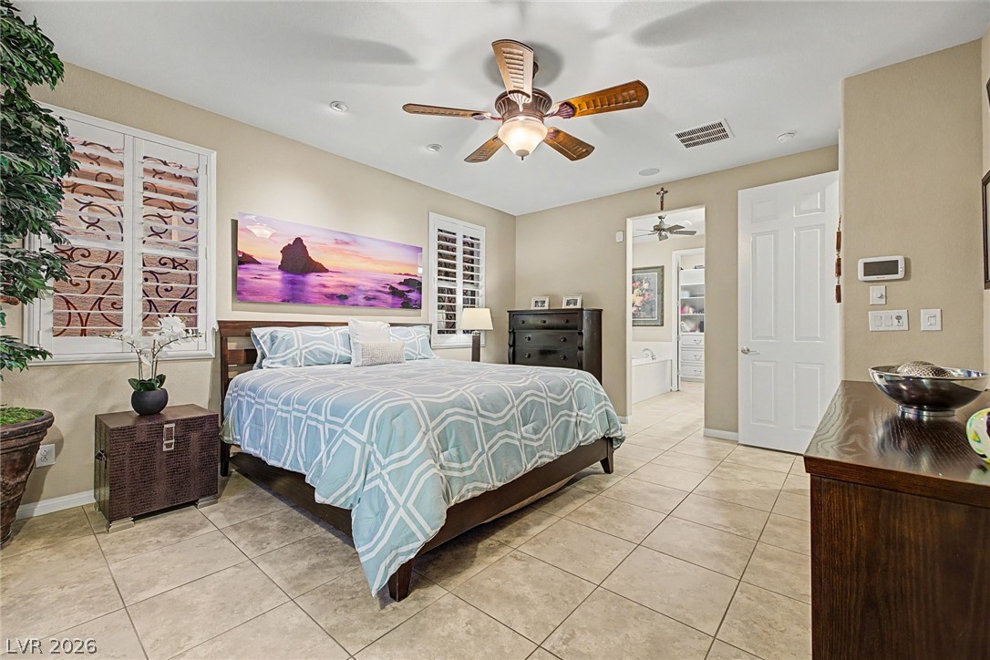 7415 Campbell Ranch Avenue Las Vegas, NV 89179 - Photo 32 of 52 Relax in this tranquil bedroom, featuring a large bed, tile flooring, and direct access to a private bathroom.