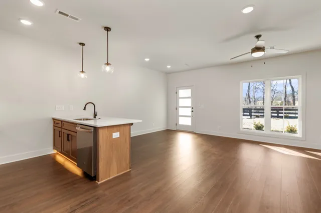 an empty room with wooden floor fireplace and windows