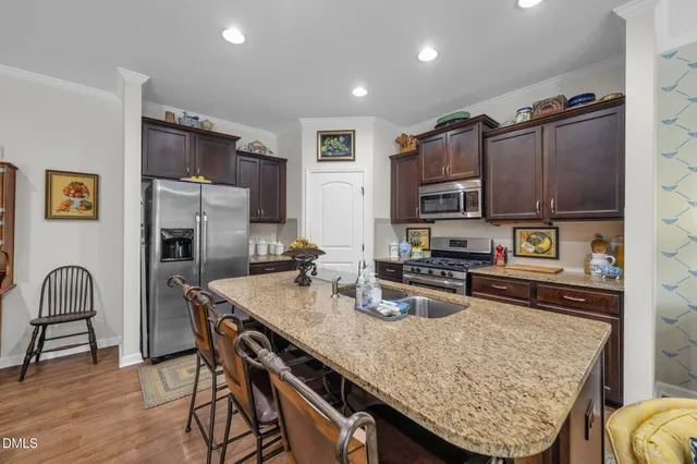 a kitchen with granite countertop a table chairs stove and refrigerator