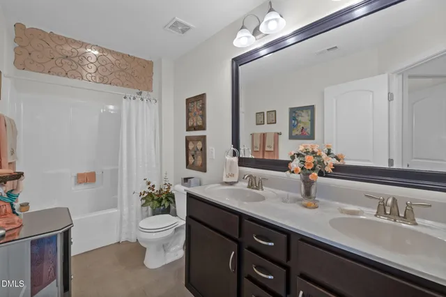 a bathroom with a double vanity sink toilet and a mirror
