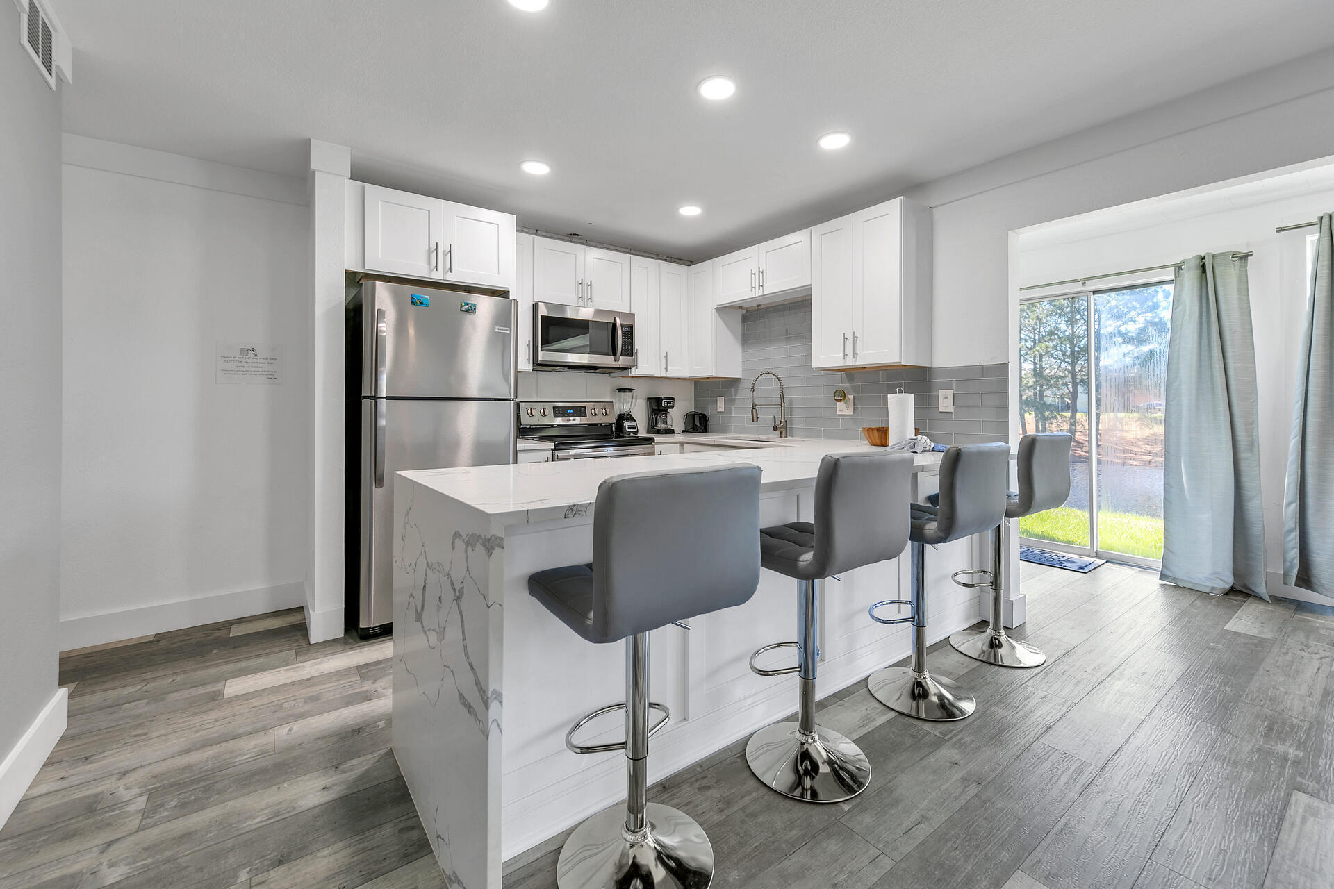 Undisclosed Address Destin, FL 32541 - Photo 11 of 23 a kitchen with kitchen island granite countertop a refrigerator a stove a sink and a dining table with wooden floor