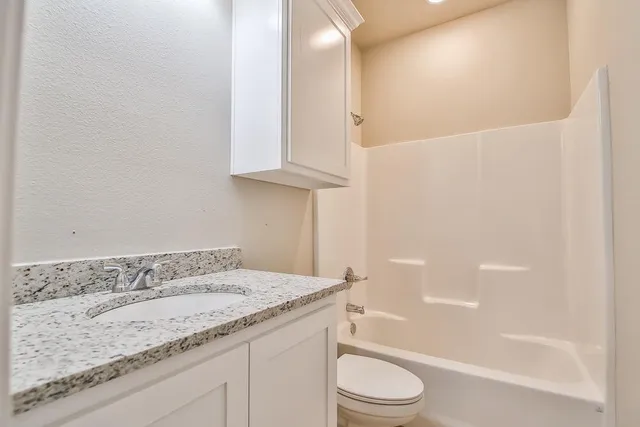 a bathroom with a granite countertop sink a toilet and bathtub