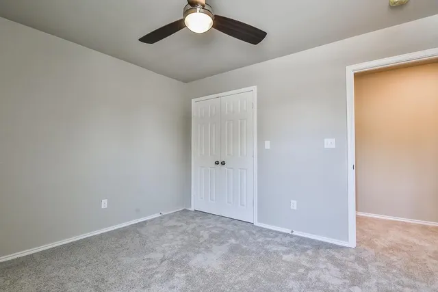 an empty room with a chandelier fan and closet