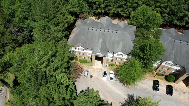 an aerial view of a house with outdoor space and trees all around