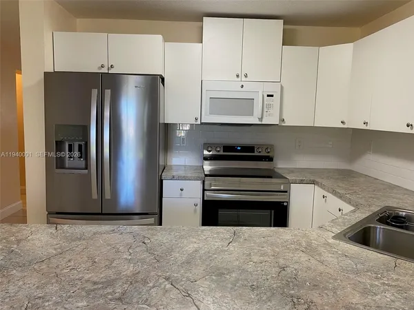 a kitchen with a refrigerator sink and cabinets