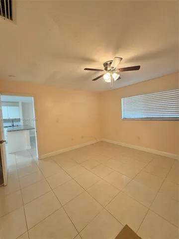 a view of a refrigerator in kitchen and an empty room