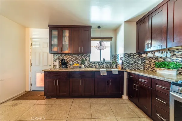 a kitchen with stainless steel appliances granite countertop a dining table chairs refrigerator and sink