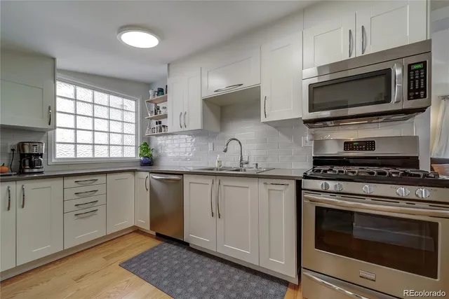 a kitchen with granite countertop a sink cabinets and stainless steel appliances