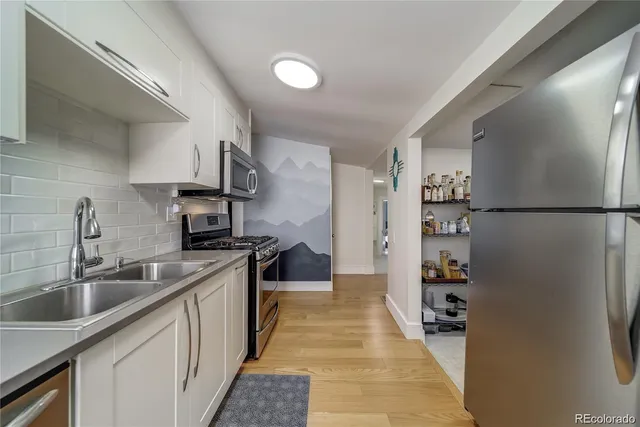 a kitchen with stainless steel appliances a refrigerator a sink a stove and white cabinets