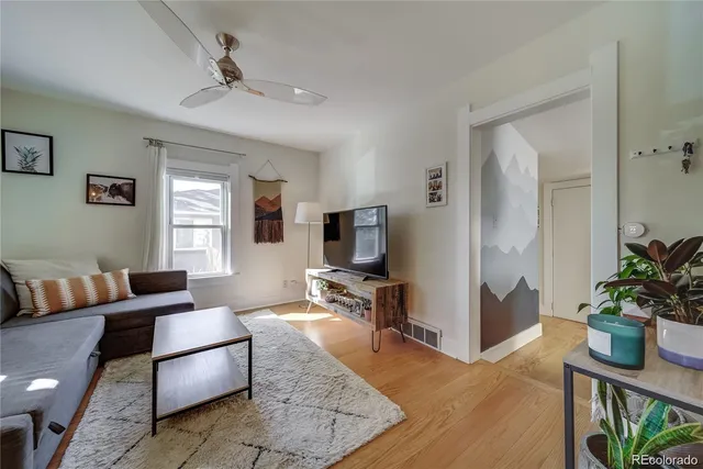a living room with furniture hard wood floor and a flat screen tv