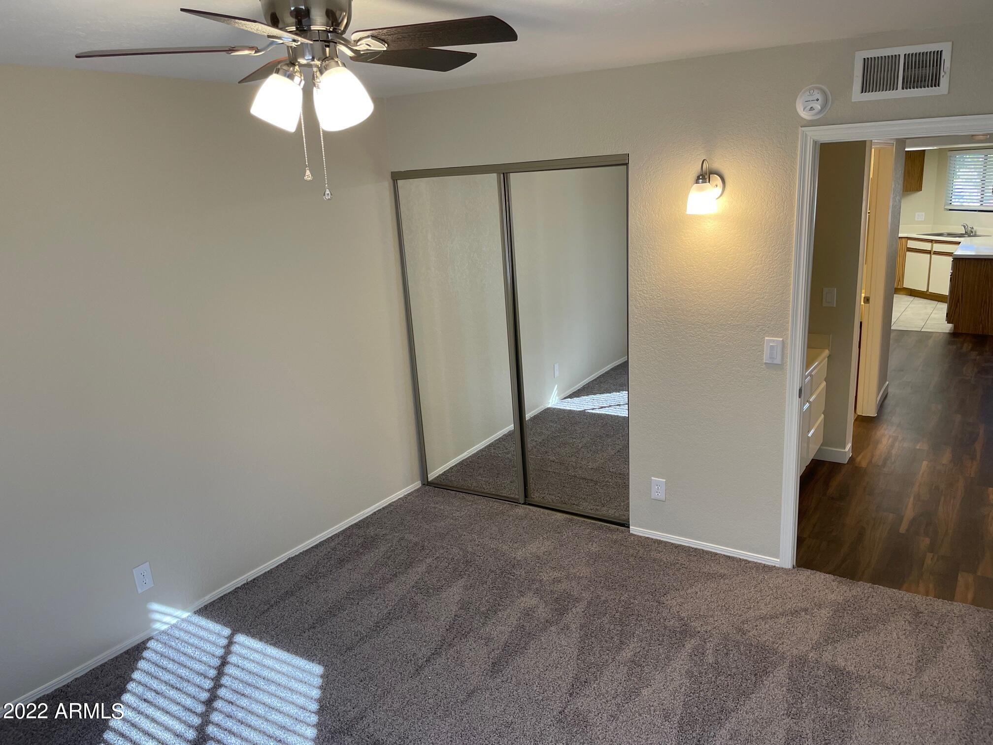 1444 North Recker Road, Unit 167 Mesa, AZ 85205 - Photo 12 of 13 a view of a hallway with a chandelier fan and wooden floor