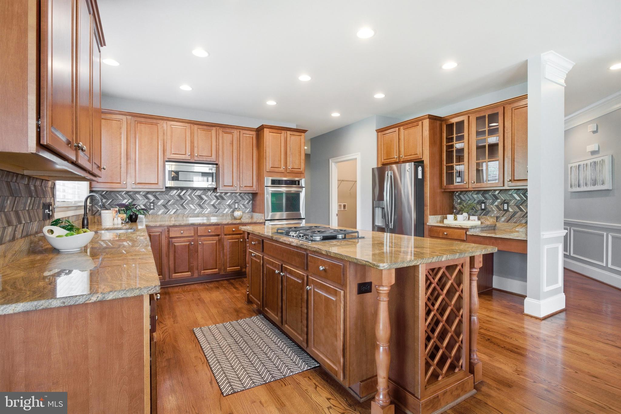 18475 Kerill Road Triangle, VA 22172 - Photo 7 of 99 a kitchen with stainless steel appliances granite countertop a stove top oven a refrigerator a sink and dishwasher with wooden floor