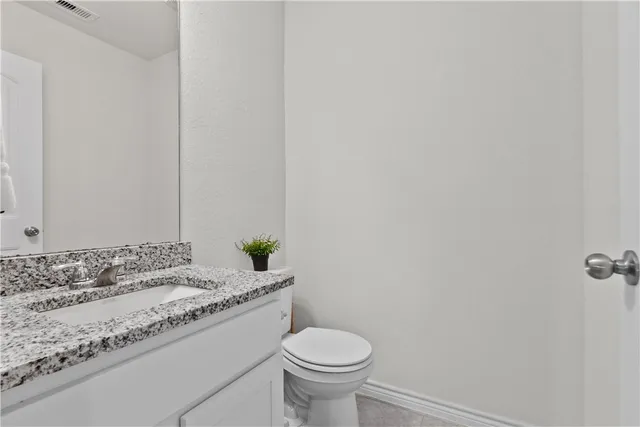 a bathroom with a granite countertop sink and a toilet