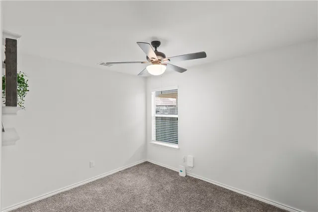 an empty room with a window and a ceiling fan