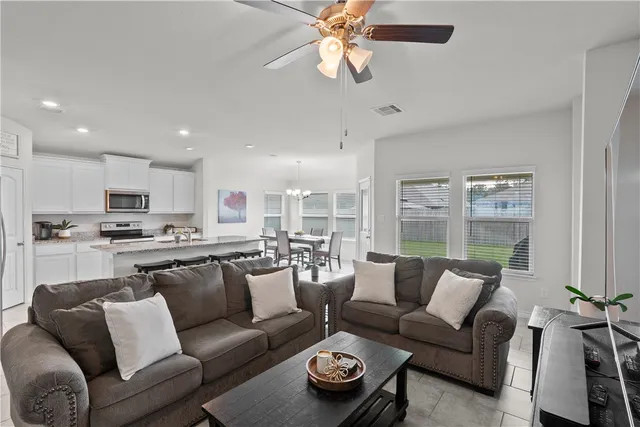 a living room with furniture kitchen area and a chandelier