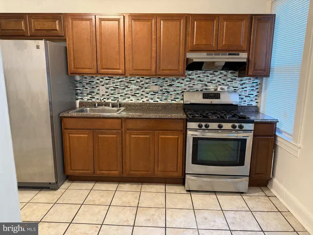 a kitchen with granite countertop a stove a refrigerator and a sink