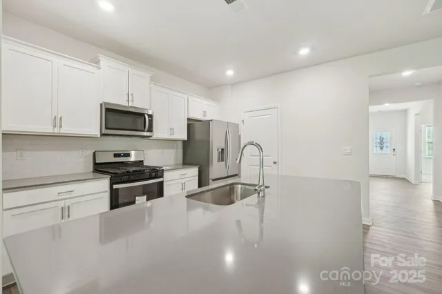 a kitchen with stainless steel appliances granite countertop a refrigerator a stove a sink a microwave and oven