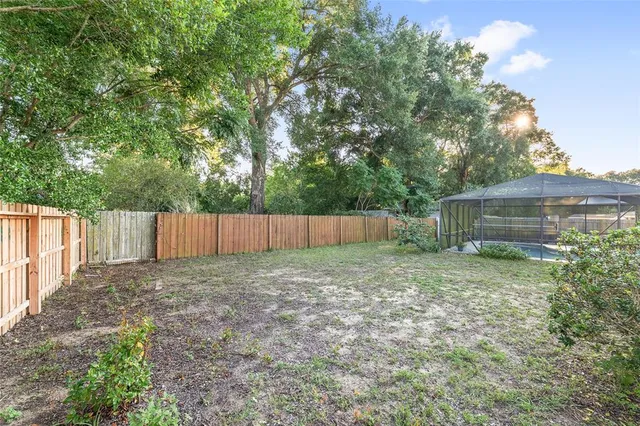 a view of a house with a yard plants and large tree