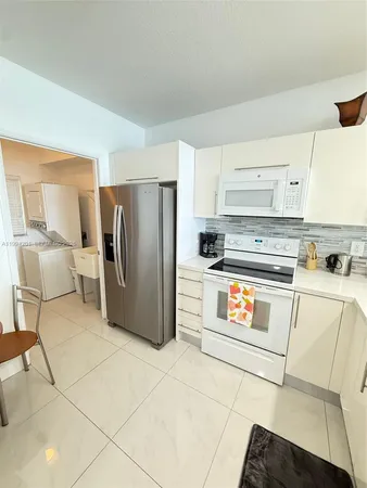 a kitchen with stainless steel appliances granite countertop a refrigerator a stove and white cabinets