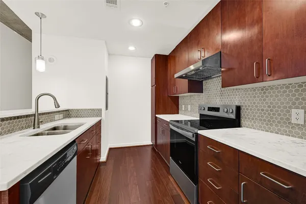 a kitchen with stainless steel appliances granite countertop a sink a stove and a wooden floors