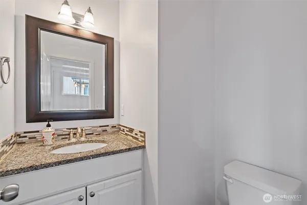 a bathroom with a granite countertop sink toilet and mirror