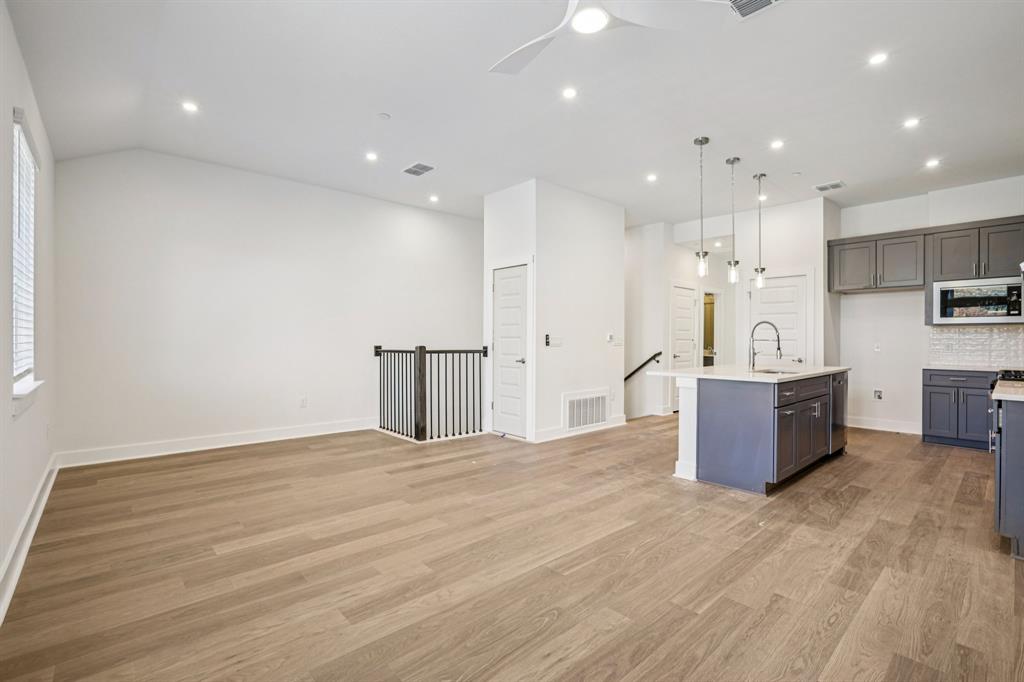 200 West 56th Street, Unit 8103 Austin, TX 78751 - Photo 6 of 13 a large room with kitchen island a stove a sink a refrigerator and white cabinets with wooden floor