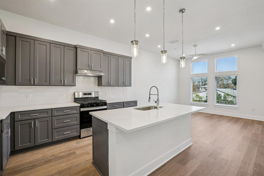 200 West 56th Street, Unit 8103 Austin, TX 78751 - Photo 7 of 13 a kitchen with stainless steel appliances granite countertop a sink a stove and a wooden floors