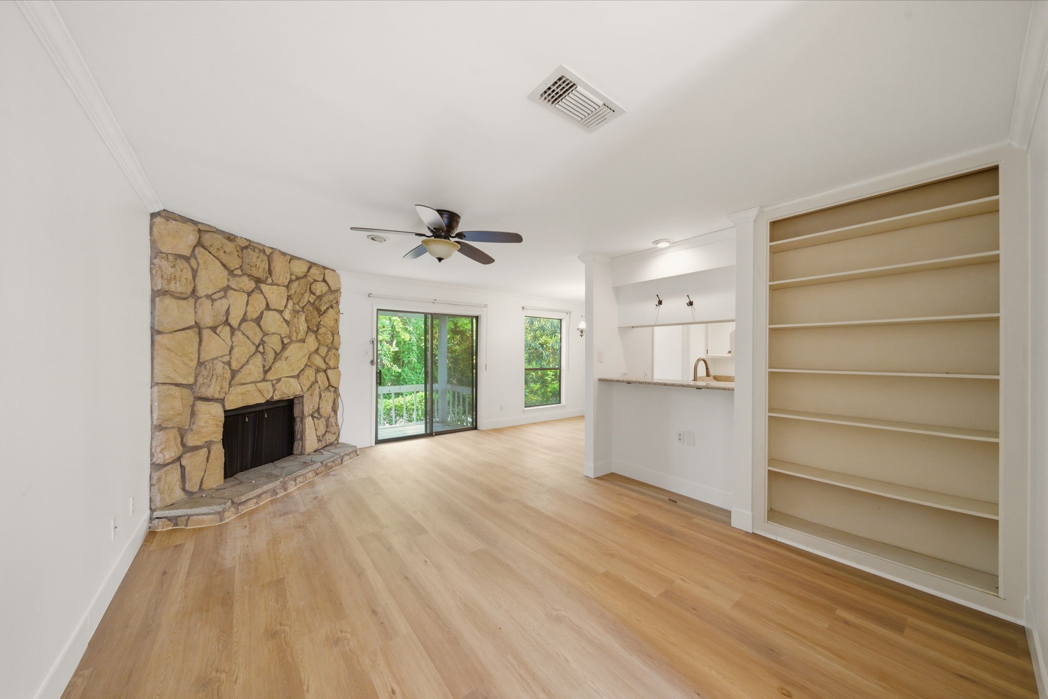 a view of a livingroom with a fireplace a ceiling fan and window