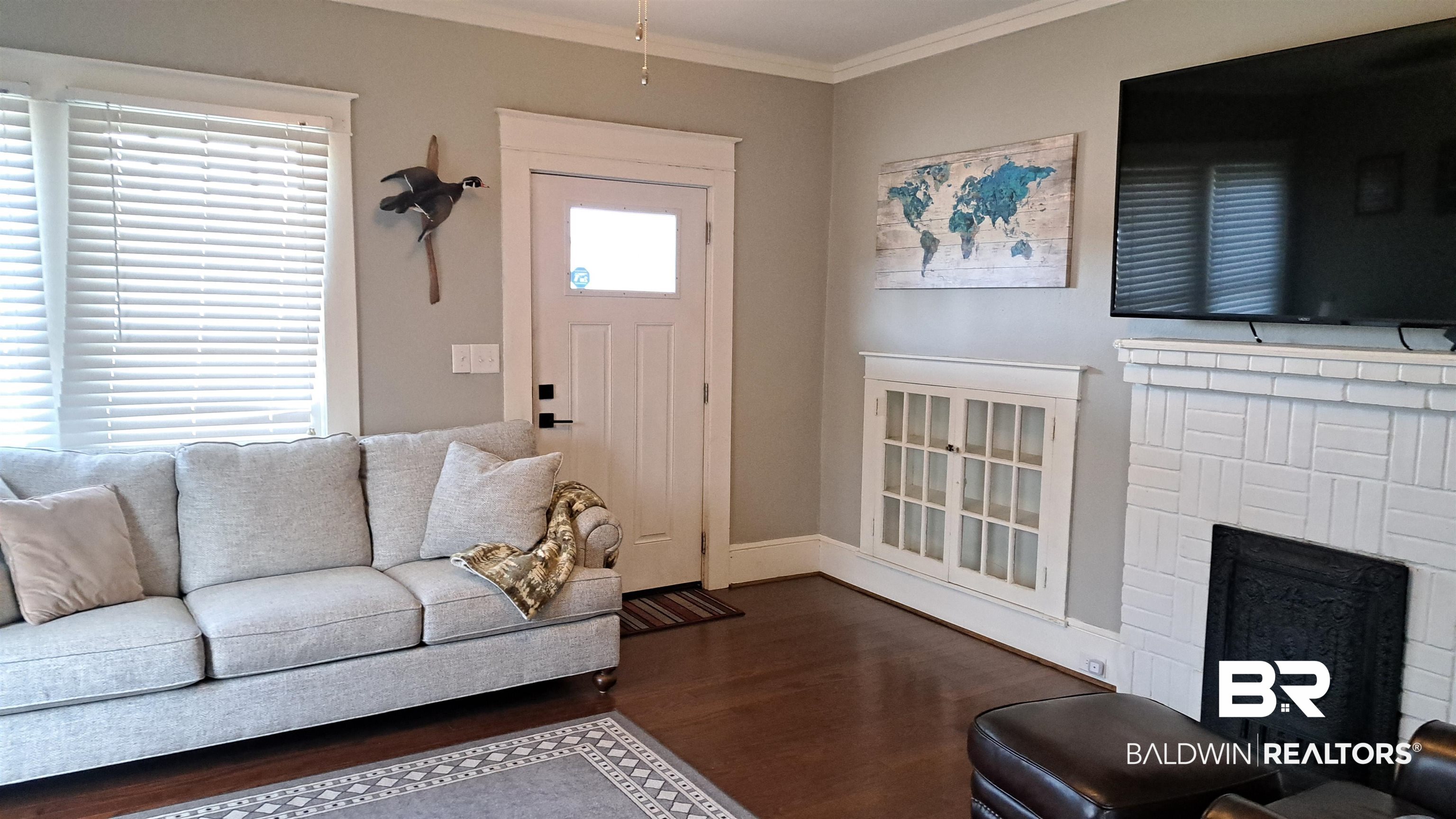 110 South Main Street Evergreen, AL 36401 - Photo 4 of 27 Living area featuring wood-finish flooring, white trim, and a decorative fireplace with a tile surround
