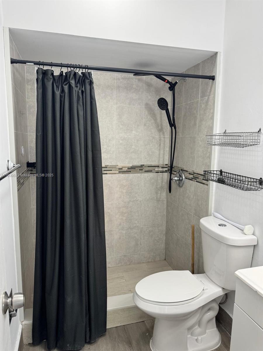 9155 Fontainebleau Boulevard, Unit 5 Miami, FL 33172 - Photo 9 of 18 a bathroom with a toilet and a shower curtain