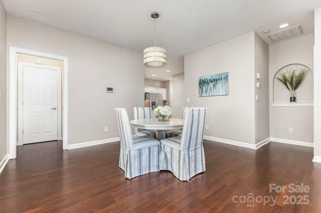 a kitchen with stainless steel appliances granite countertop a sink a stove a refrigerator and white cabinets with wooden floor