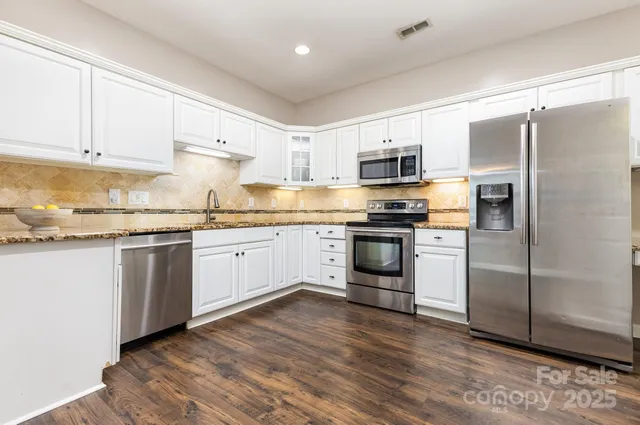 a kitchen with a white cabinets and wooden floor