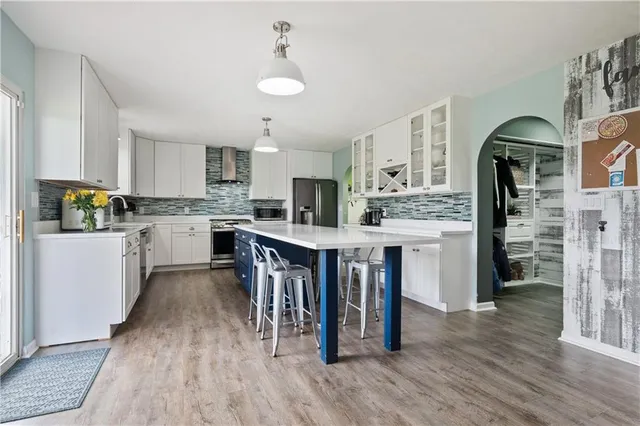 a kitchen with stainless steel appliances kitchen island wooden floors and refrigerator
