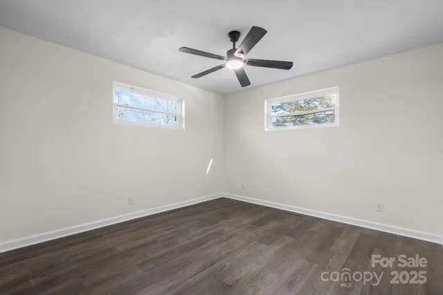 an empty room with wooden floor and ceiling fan