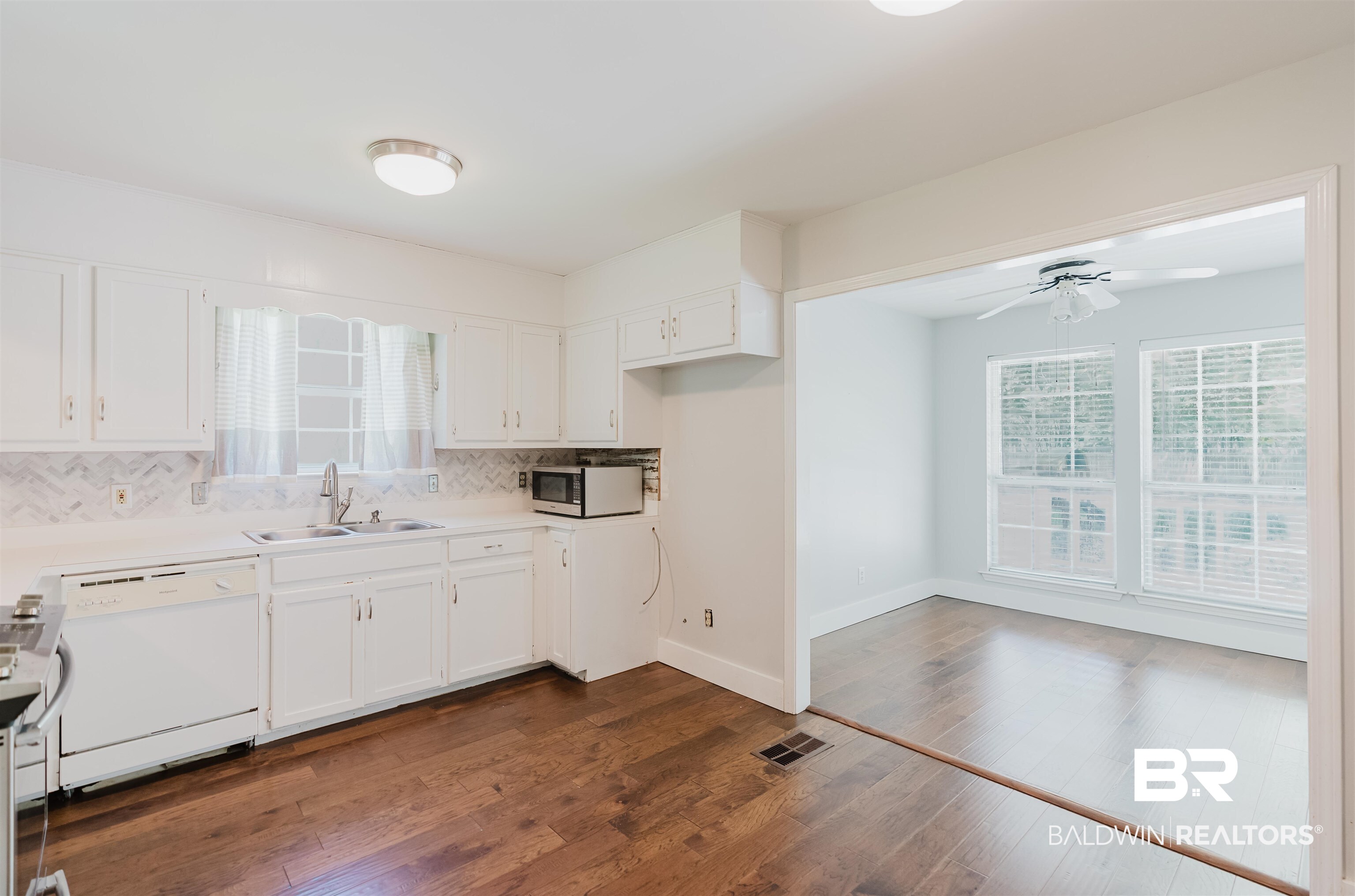 20460 Bishop Road Fairhope, AL 36532 - Photo 26 of 41 Kitchen featuring dishwasher, a sink, ceiling fan, decorative backsplash, and white cabinetry