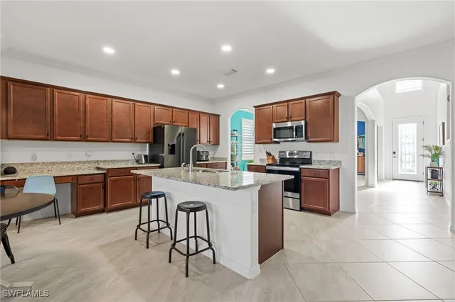 a kitchen with granite countertop wooden cabinets a sink a stove a oven with dining table and chairs