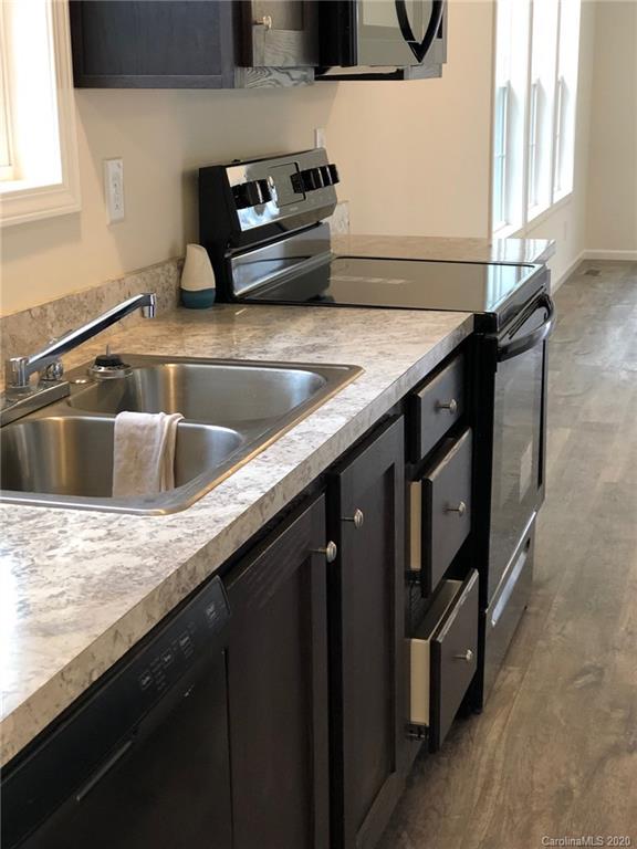 296 Souther Road Fletcher, NC 28732 - Photo 16 of 25 a kitchen with granite countertop a sink a stove and wooden cabinets