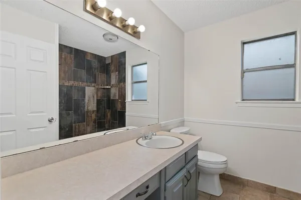 a bathroom with a sink vanity granite toilet and a mirror