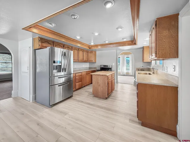 a kitchen with stainless steel appliances granite countertop a refrigerator a sink a stove and a wooden floors