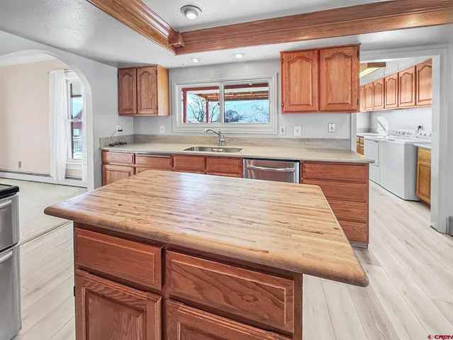 a kitchen with kitchen island a counter top space a sink wooden floor and a window